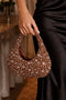 Hand holding a beaded clutch purse with a blurred indoor background