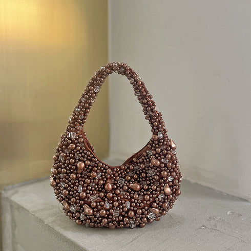 Brown beaded handbag on a light surface with a neutral background
