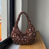 Decorative handbag with beads and crystals on a wooden surface near a window.