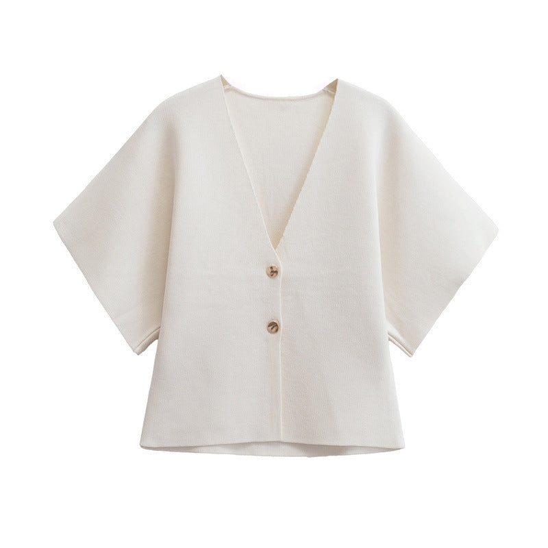 White cape-style jacket with gold buttons on a white background